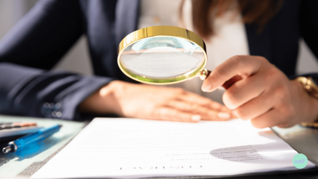 Une femme observe un contrat à la loupe.