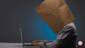 Un homme masqué tape sur un ordinateur.