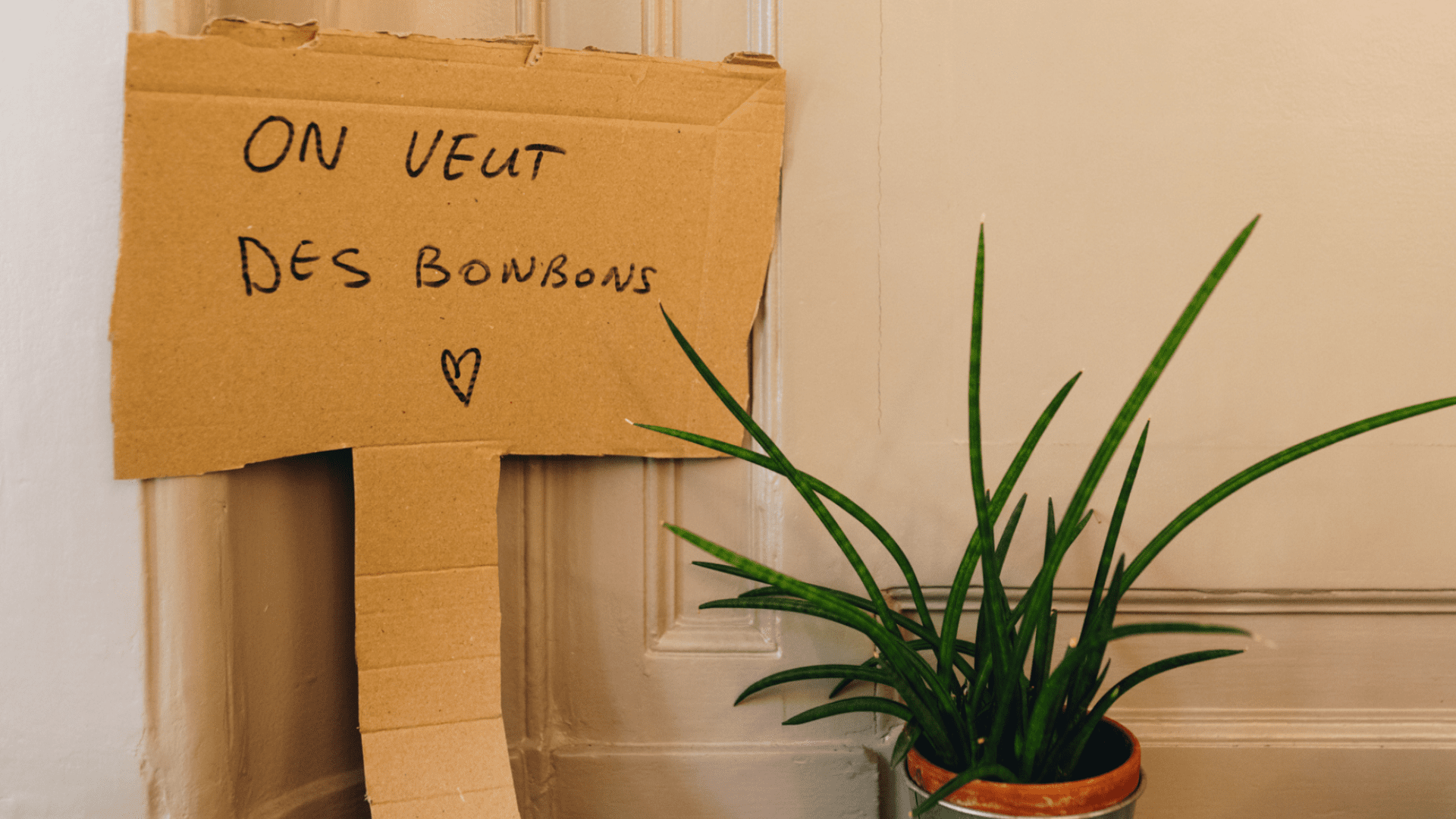 Une pancarte en carton sur laquelle il est écrit : On veut des bonbons.