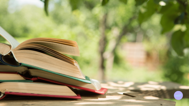 Une pile de livres ouverts sur une table en extérieur.