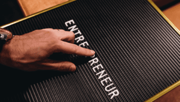 Sur un tableau noir, il est écrit Entrepreneur. Quelqu'un est en train d'ajouter une lettre au mot.