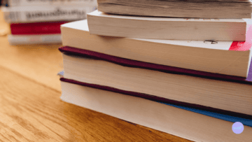 Plusieurs livres sont empilés sur une table.