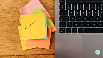 Une pile de post it au sommet de laquelle il est écrit Franchise, à côté d'un ordinateur.