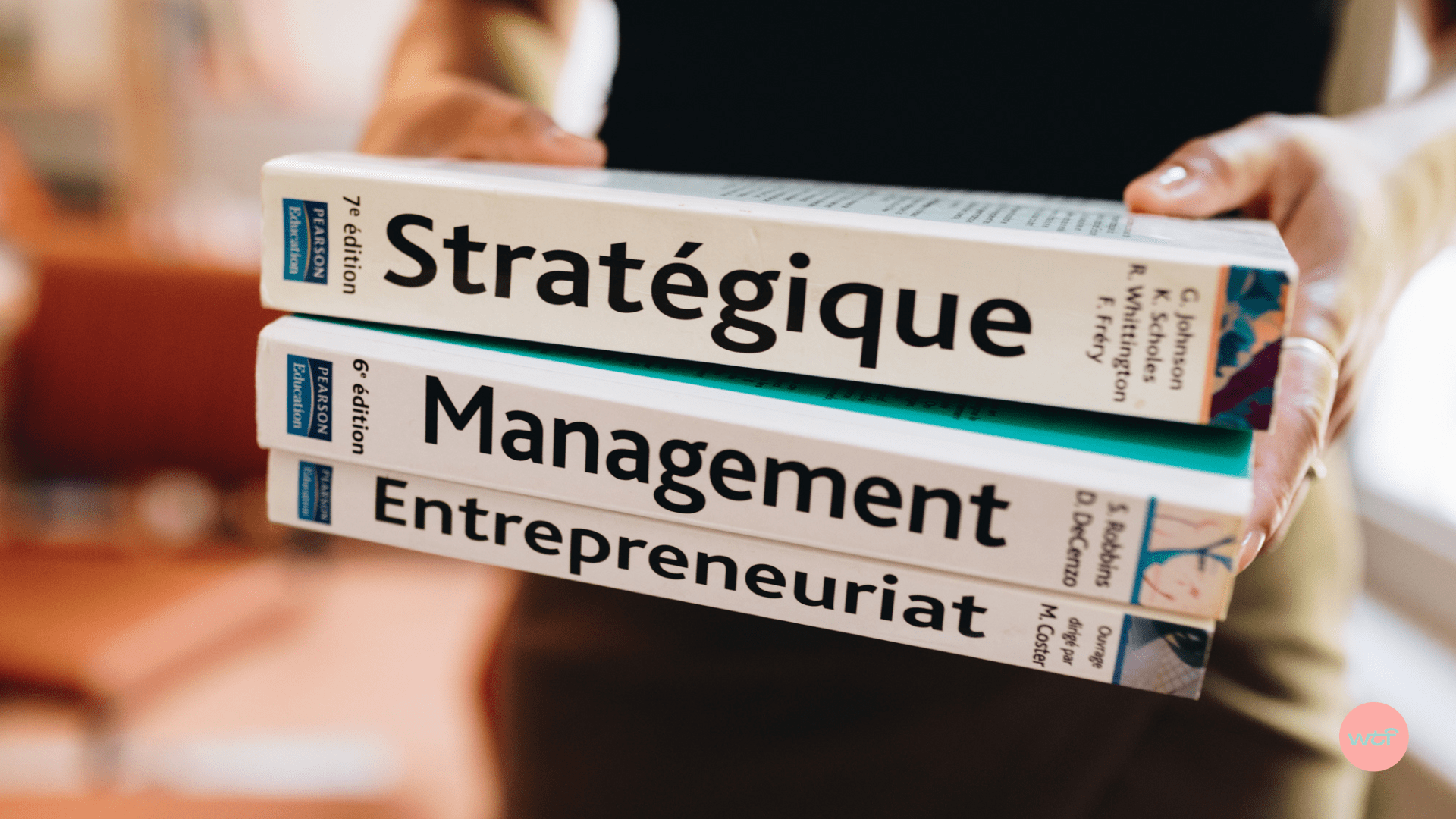 Un homme porte trois livres sur le management, la stratégie et l'entrepreneuriat.