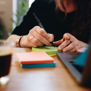 Une femme dessine un soleil sur un post it.