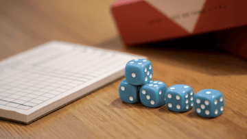 Des dès empilés devant un carnet.