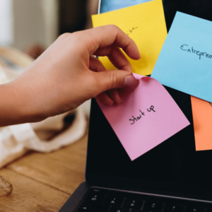 Sur un écran d'ordinateur, plusieurs post it multicolores sont collés. Quelqu'un décolle le post it où il est noté Start up.