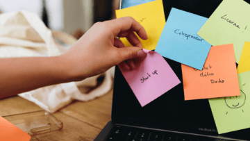 Sur un écran d'ordinateur, plusieurs post it multicolores sont collés. Quelqu'un décolle le post it où il est noté Start up.