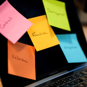Un post it jaune sur lequel il est noté Franchise est collé sur un écran avec d'autres post it multicolores.