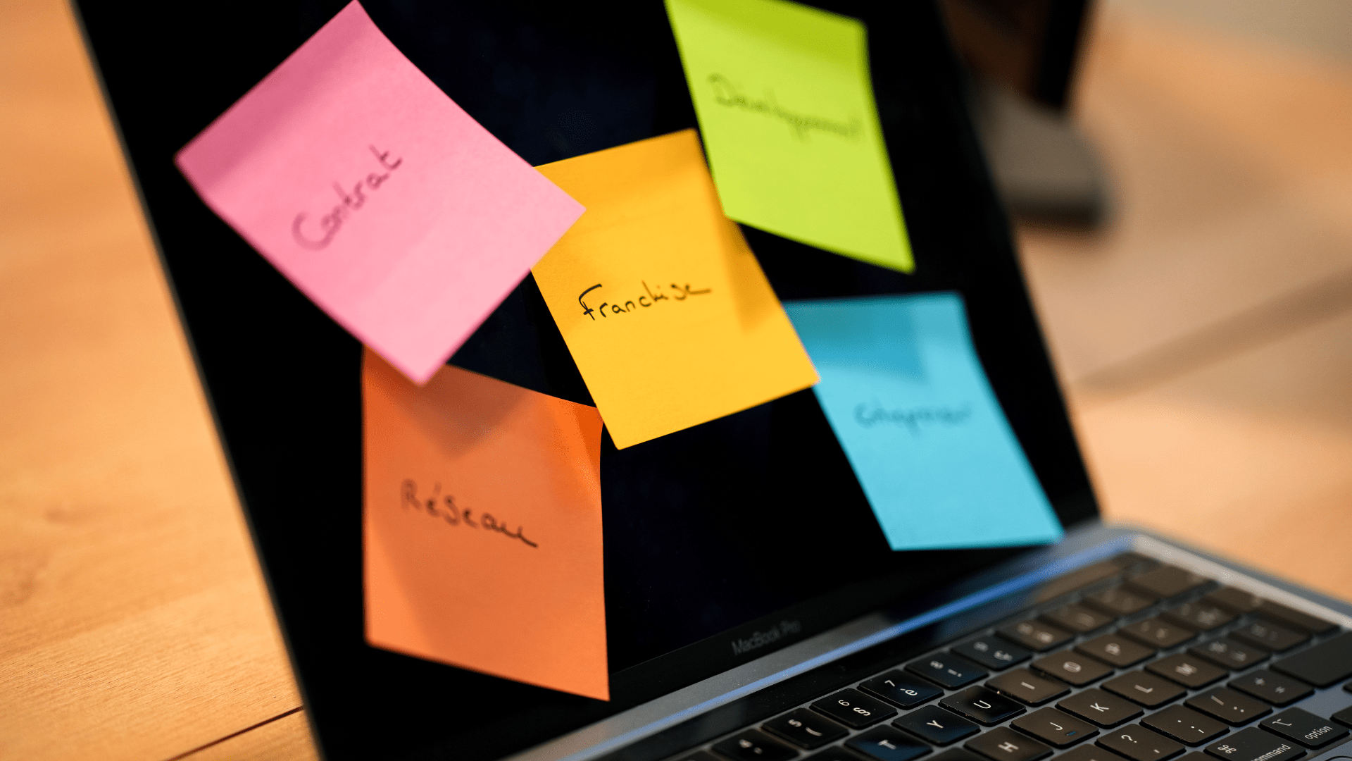 Un post it jaune sur lequel il est noté Franchise est collé sur un écran avec d'autres post it multicolores.