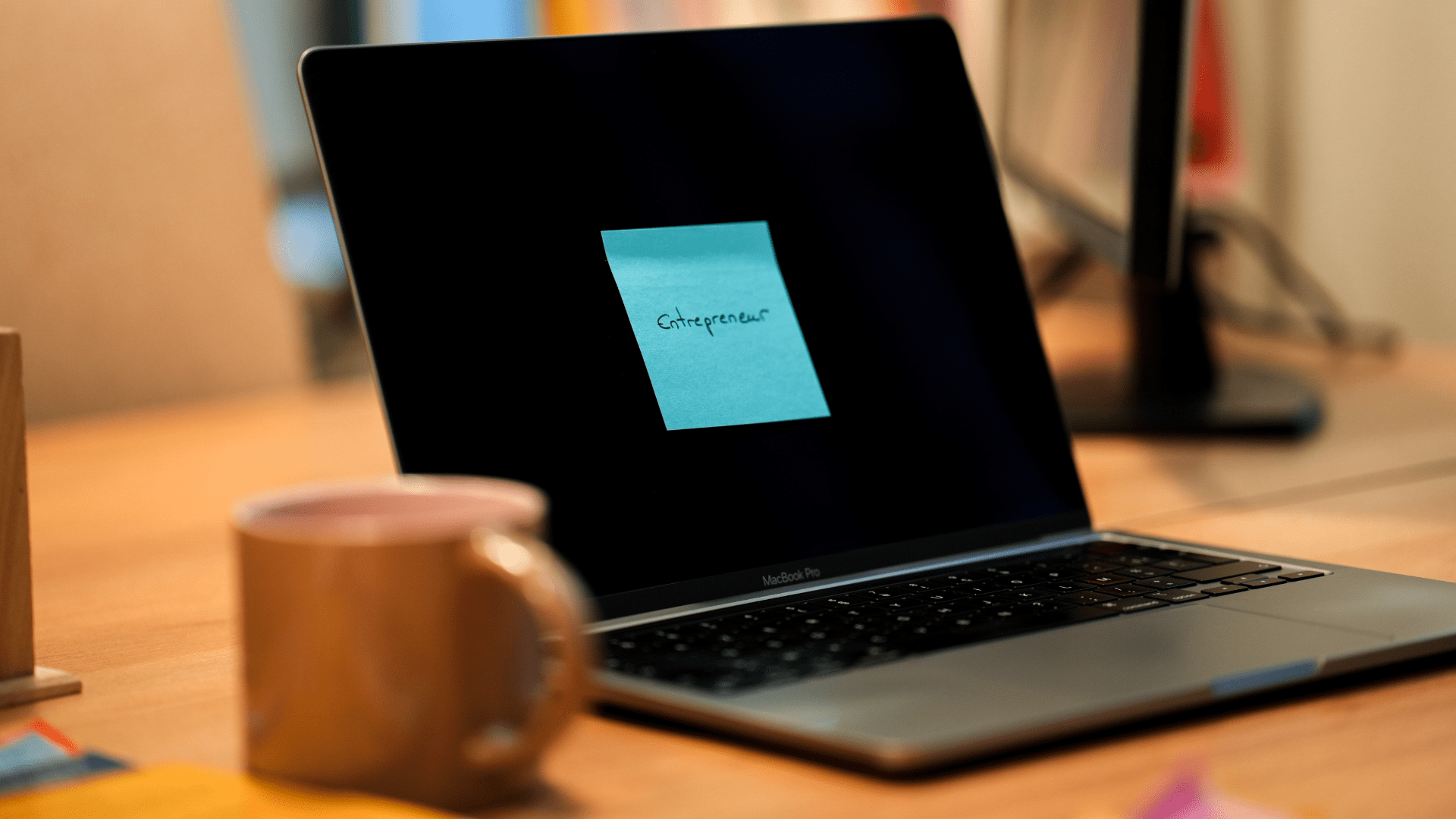 Un post it bleu sur lequel il est écrit Entrepreneur est collé sur un écran d'ordinateur.