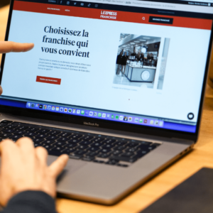 Un écran d'ordinateur sur lequel est affiché une page franchise. Quelqu'un la pointe du doigt.