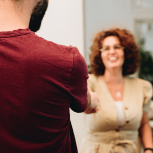 Un homme de dos sert la main d'une femme pour lui souhaiter la bienvenue.
