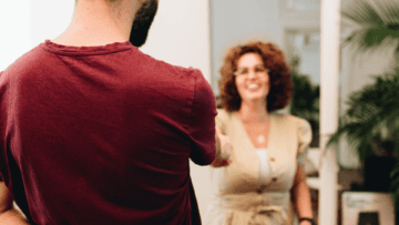 Un homme de dos sert la main d'une femme pour lui souhaiter la bienvenue.