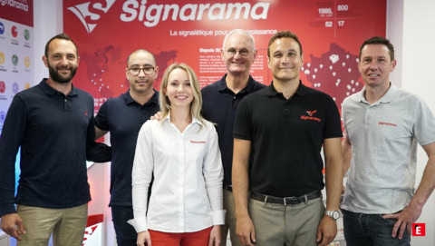 Équipe signarama devant un stand rouge