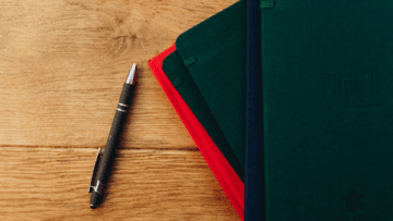 Un stylo et des carnets pour illustrer le contrat de réservation de zone en franchise.