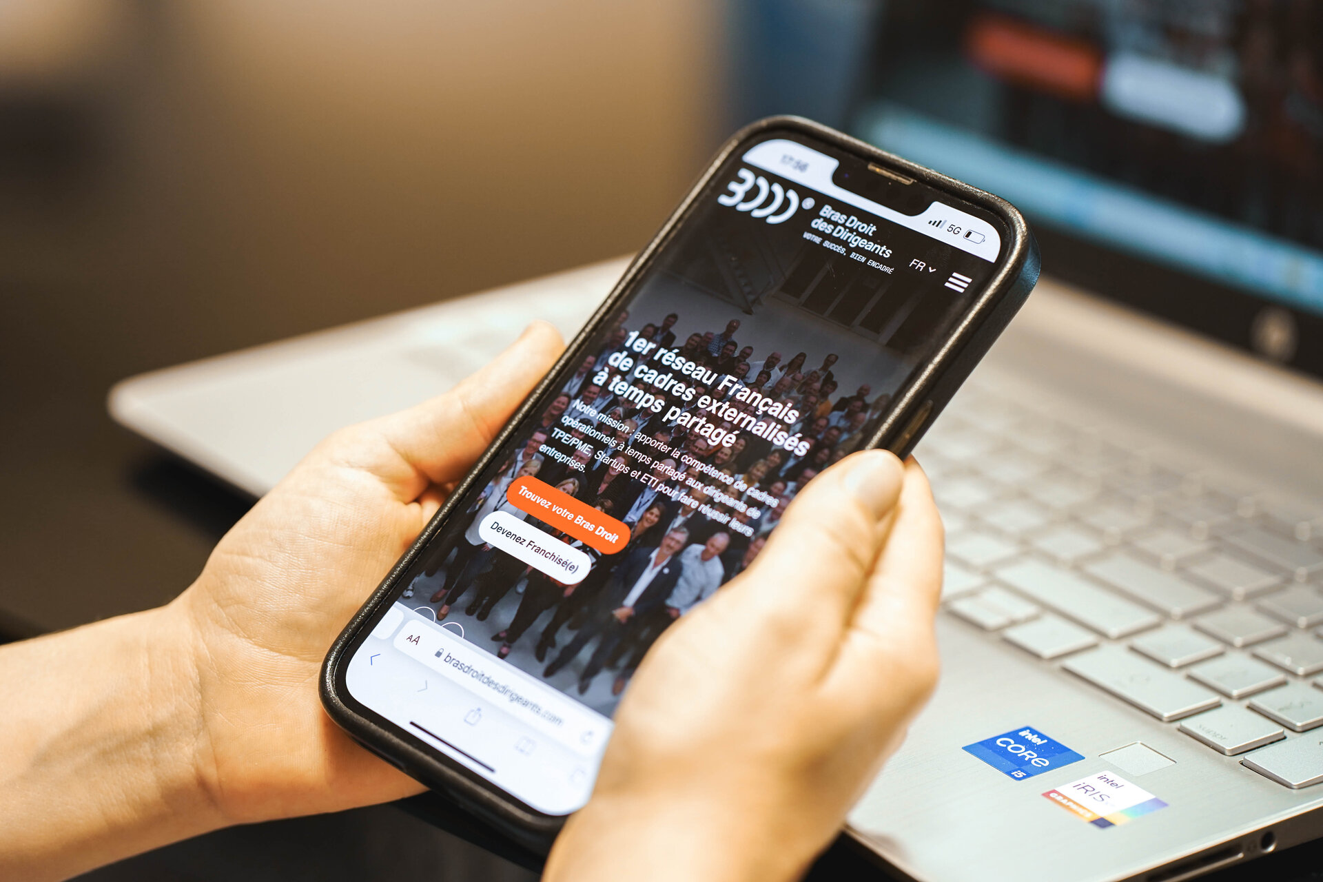 Des mains tenant un téléphone qui montre le site de bras droits des dirigeants
