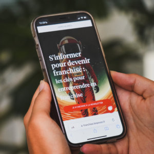 Un téléphone portable sur lequel est affichée la page d'accueil de L'Express Franchise.