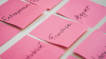 Plusieurs post its roses sur lesquels sont écrit les mots entrepreneur, apport, etc. Le mot clé franchise est mis en avant au centre.