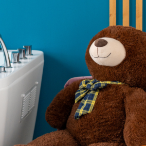 Un ours en peluche installé à côté d'une baignoire.