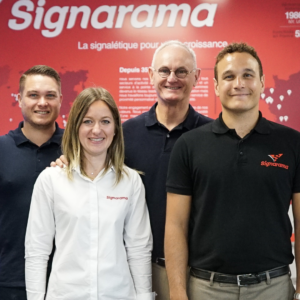 Les équipes de Signarama, devant une bâche portant leur logo.