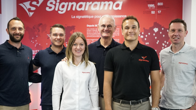 Les équipes de Signarama, devant une bâche portant leur logo.