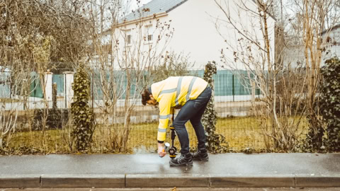 ouvrier en gilet jaune pulvérise le trottoir humide