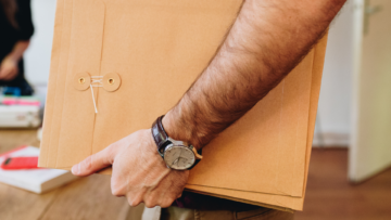 Un homme tient plusieurs enveloppes en papier kraft.