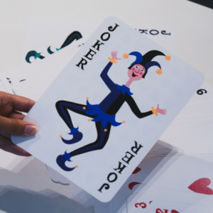 Une grosse carte joker tenue par une femme.