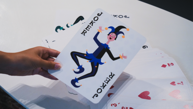 Une grosse carte joker tenue par une femme.