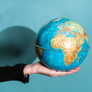 Une personne tient dans sa main un globe sur un fond bleu.