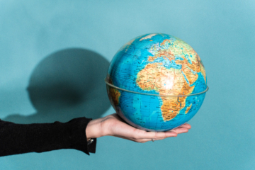 Une personne tient dans sa main un globe sur un fond bleu.