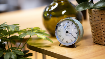 Un réveil matin posé sur une table en bois indique 3h55.