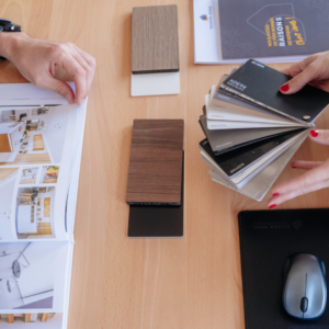 Un client feuillette un catalogue d'ameublement tandis que sa conseillère lui montre des échantillons.