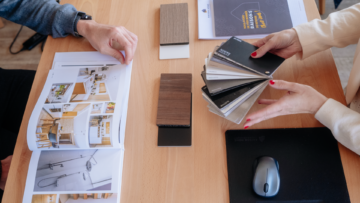 Un client feuillette un catalogue d'ameublement tandis que sa conseillère lui montre des échantillons.