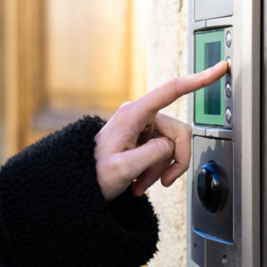Une personne sonne à un interphone d'immeuble.