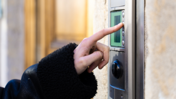 Une personne sonne à un interphone d'immeuble.