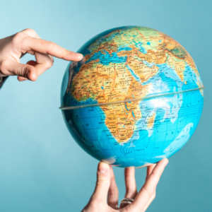une main et un doigt qui pointe un pays sur le globe