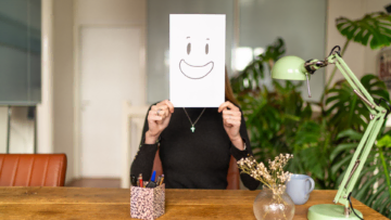 personne avec un papier sur lequel un visage est dessiné