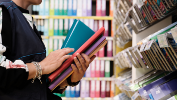 Une personne range des cahiers dans les rayons d'un magasin.