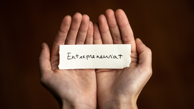 Une personne tient dans le creux de ses mains une étiquette "Entrepreneuriat"