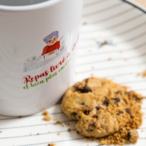 Sur une assiette en porcelaine, un cookie et un mug sont posés.