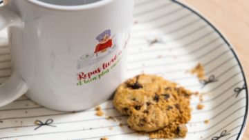 Sur une assiette en porcelaine, un cookie et un mug sont posés.