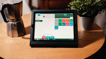 Sur une table est posée une tablette de restaurateur et une cafetière italienne.