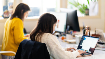 Deux salariés d'une entreprise travaillent sur leurs ordinateurs côte à côte.