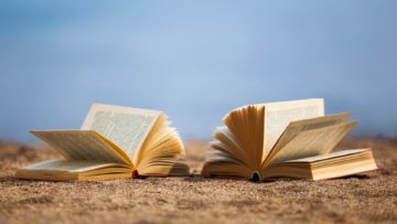 Deux livres ouverts sur une plage de sable.