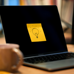 Un post it jaune avec une ampoule dessinée dessus est collé sur un écran d'ordinateur.