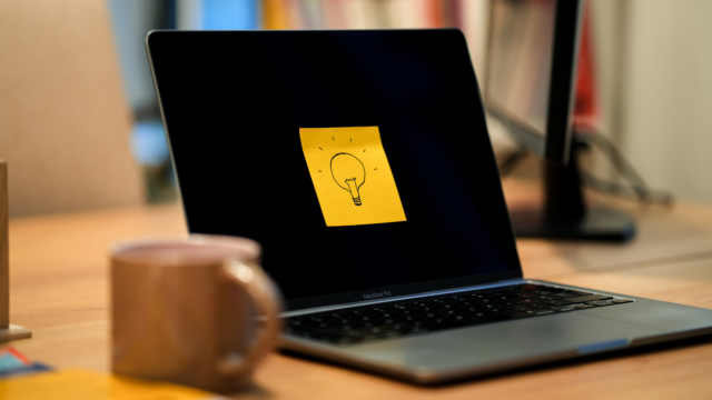 Un post it jaune avec une ampoule dessinée dessus est collé sur un écran d'ordinateur.