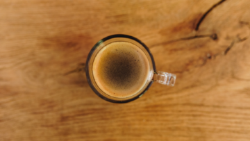 Une tasse de café vue du dessus posée sur une table en bois.