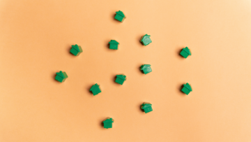 Plusieurs maisons de Monopoly vertes sur un fond orange.